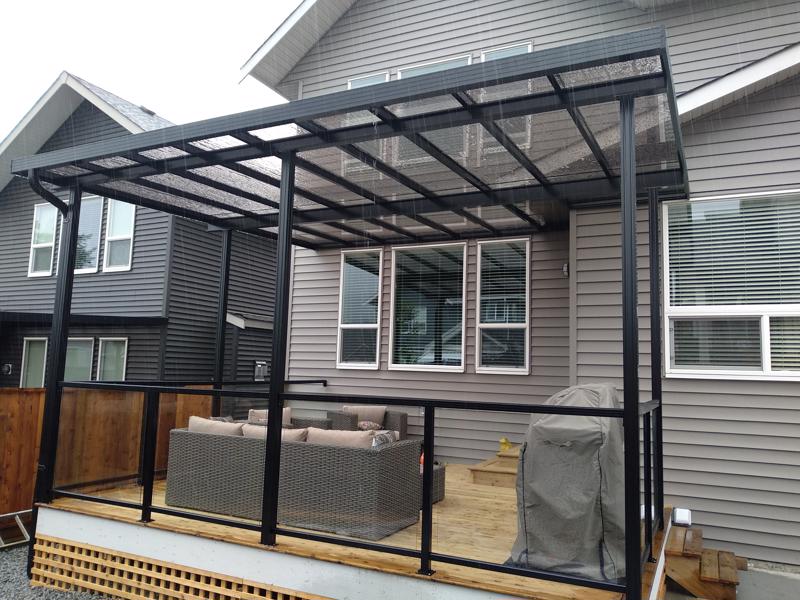 Glass patio cover with black trim and black posts.